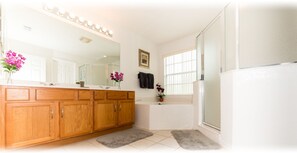 A modern bathroom with a wooden vanity, a large mirror, and a shower area.