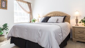 A neatly arranged bedroom with a large bed, bedside tables, and a window with curtains. - 5BR Davenport Pool Home by Watson-465GE (Davenport)