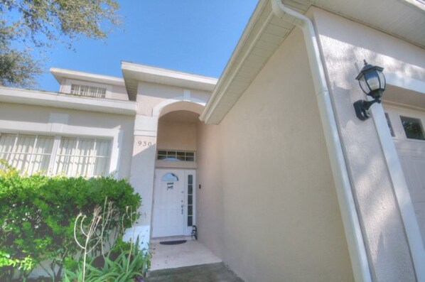A beige house with a white garage door, a small front porch, and a mailbox.