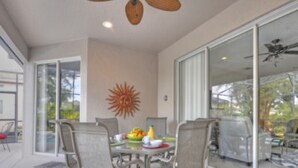 A modern dining area with a glass table, metal chairs, and a ceiling fan. - 5BR Haines City PoolHome by Watson-186MN (Haines City)