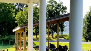 Un patio techado con mobiliario exterior, columnas y plantas en macetas.