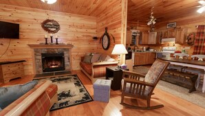 Interior acogedor de una cabaña con chimenea, muebles de madera, un comedor y una cocina.