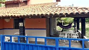 Une maison avec un toit en tuiles, une clôture bleue et un hamac.