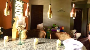 Un espace repas avec une table en granit, des suspensions en cuivre et des chaises en osier.