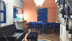 Un salon avec un canapé noir, un coin repas avec des tables bleues et un escalier.