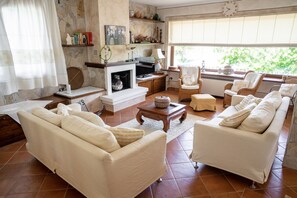 Cozy living room with a fireplace, sofas, and a wicker armchair.