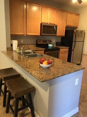Enjoy cooking in this well-equipped kitchen with a refrigerator, microwave, and oven, and sit at the bar with a bowl of fresh fruit.