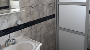 A bathroom with a white sink, a mirror, and a shower enclosure. - Beautiful house in Country steps from the Paraná River (Ituzaingo)