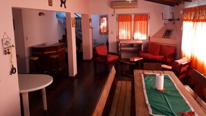 A cozy living room with a wooden table, red chairs, a sofa, and a ceiling fan. - Beautiful house in Country steps from the Paraná River (Ituzaingo)