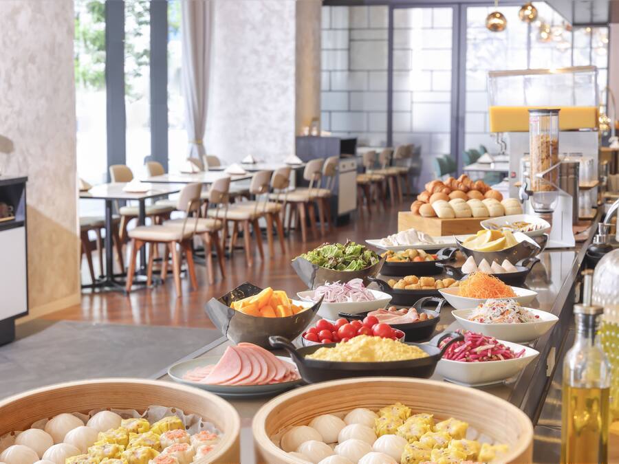 Ein reichhaltiges Buffet mit verschiedenen Speisen und ein Sitzbereich mit Tischen und Stühlen.
