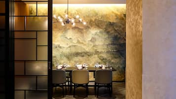 A dining area with a marble wall, a chandelier, and a table set for four.