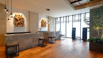 A modern reception area with a marble counter, wooden flooring, and contemporary lighting fixtures.