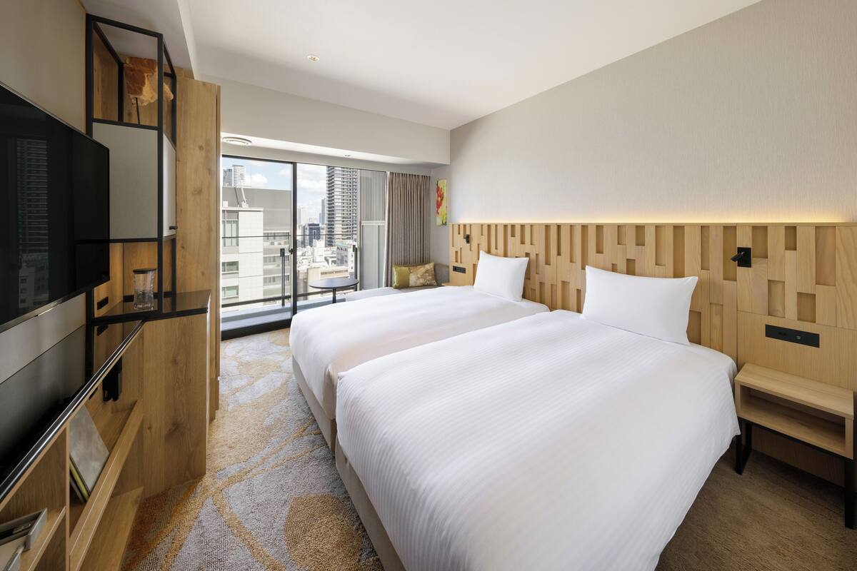 Een hotelkamer met een groot bed, een televisie en uitzicht op de stad.