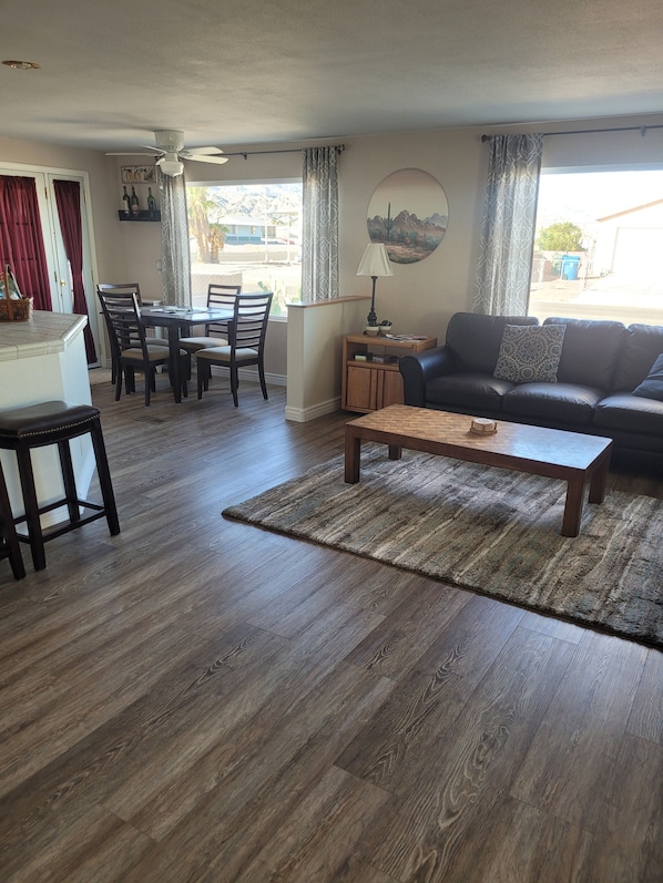 A living room with a dining area, a sofa, a coffee table, and a ceiling fan.