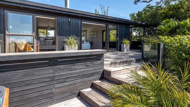 Una casa moderna con ventanas amplias, una terraza y una chimenea.