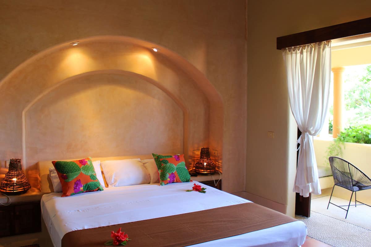 Habitación de hotel con una cama grande, techo curvo y vistas a zonas verdes.