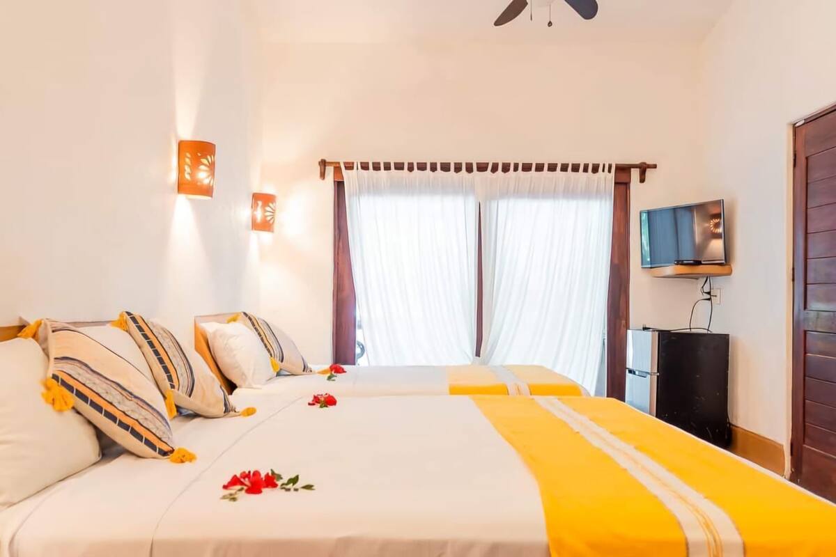 Una habitación de hotel con una cama grande, televisión y ventilador de techo.