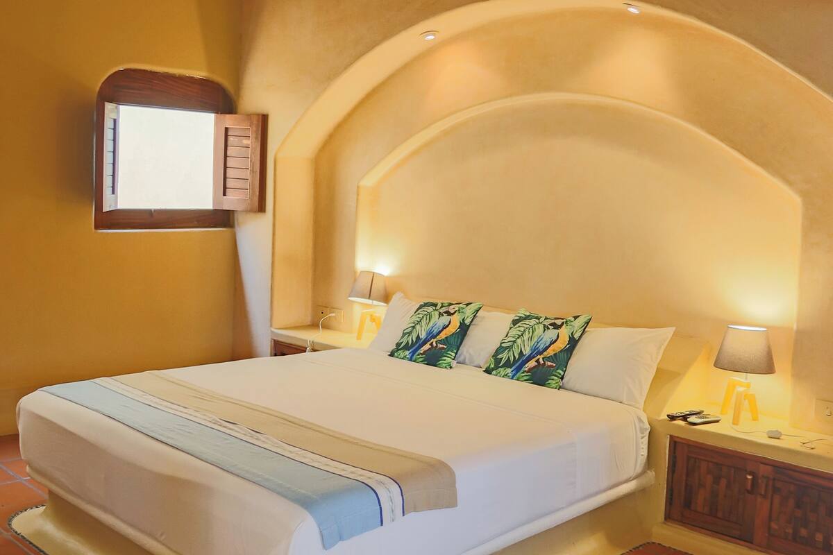 Un dormitorio con una cama, un ventilador de techo, una mesita de noche y una lámpara de pared.
