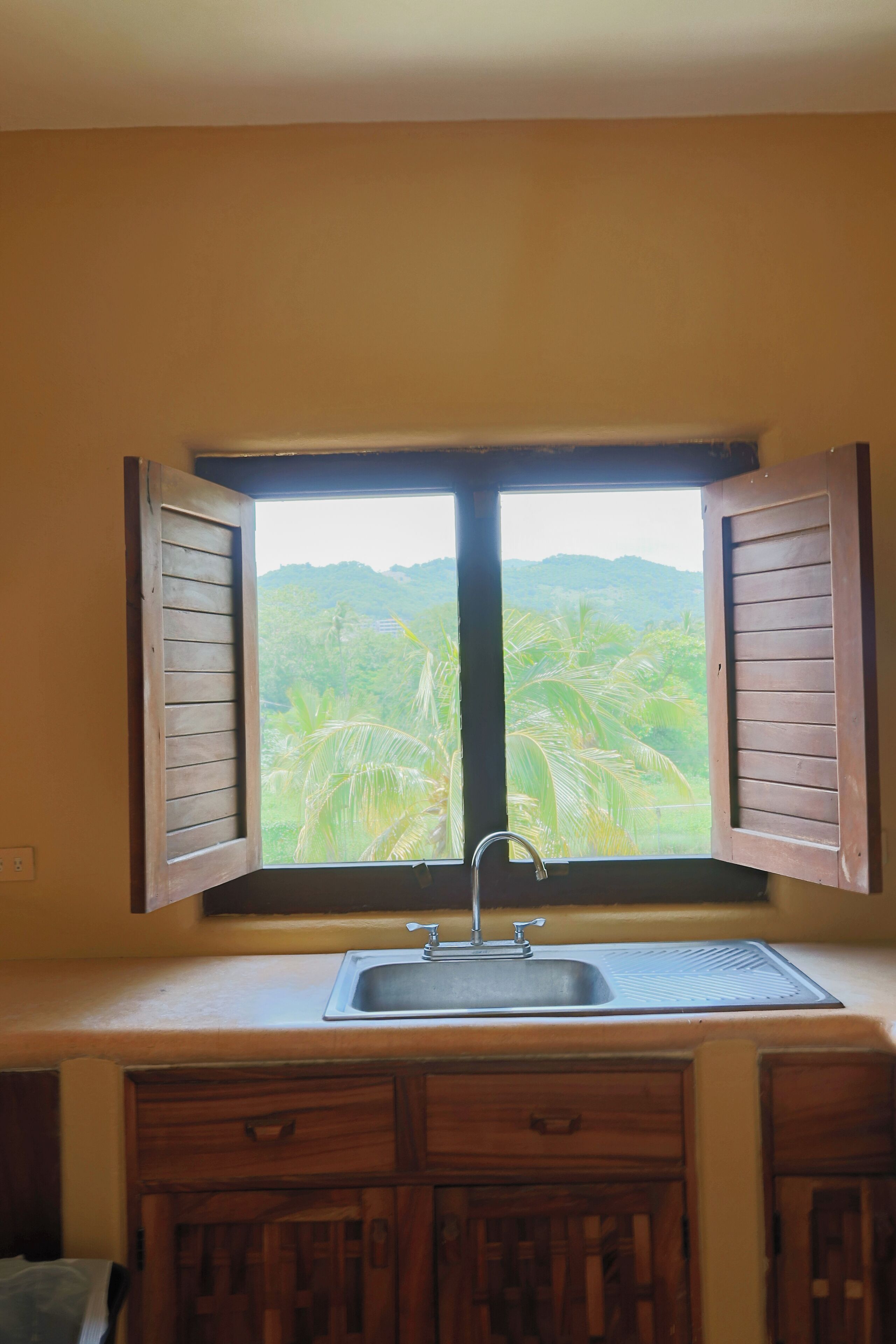 Una cocina con ventana que da a un paisaje exuberante.