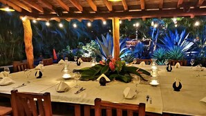 An outdoor dining area with a table set for a meal, surrounded by wooden chairs.
