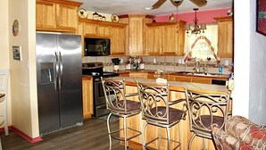 Una cocina con armarios de madera, un refrigerador de acero inoxidable, un microondas, una estufa y un ventilador de techo.
