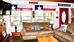 Una sala de estar acogedora con un sofá seccional, un televisor y un letrero que dice 'Lake Sweet Lake'.