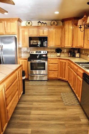 A kitchen with wooden cabinets, a stainless steel refrigerator, a stove, and a dishwasher.