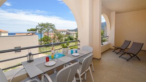 A balcony with a table set for two, a chair, and a bottle of wine. - 2 bedroom nice apartment in Algajola (Algajola)