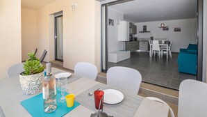 A dining area with a table set for two, a potted plant, and a bottle of water. - 2 bedroom nice apartment in Algajola (Algajola)