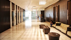 A modern hotel lobby with a long corridor, a reception desk, and seating areas. - Fort Victoria BGC Netflix 25M WiFi (Taguig)