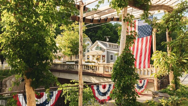 A house with a porch, a large American flag, and a garden with a fence. - The Lodge at Mount Snow (West Dover)