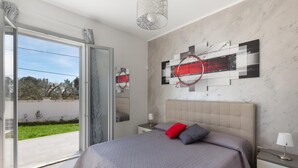 Een moderne slaapkamer met een groot bed, een glazen deur naar een balkon en een eigentijds kunstwerk aan de muur.