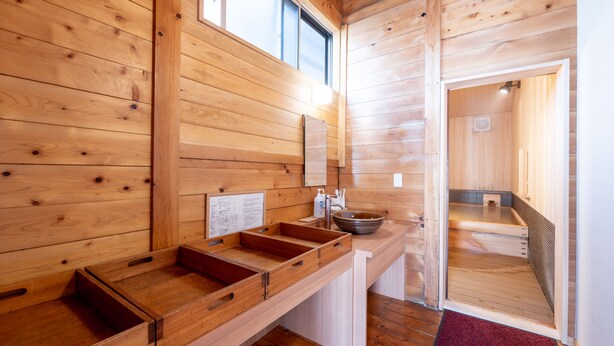 Interior de una cabaña de madera con mostrador, lavamanos y ventana.