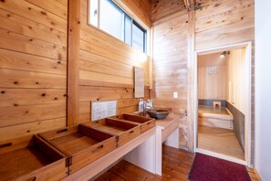 Interior de una cabaña de madera con mostrador, lavamanos y ventana.