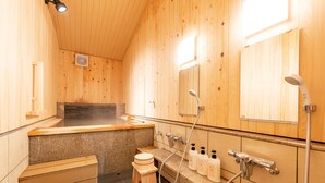 Un interior de madera con sauna, un banco de madera, un inodoro pequeño y un espejo.