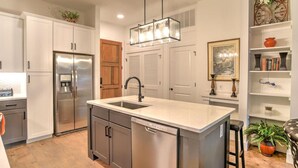 A modern kitchen with stainless steel appliances, a central island with a sink, and a pendant light fixture.