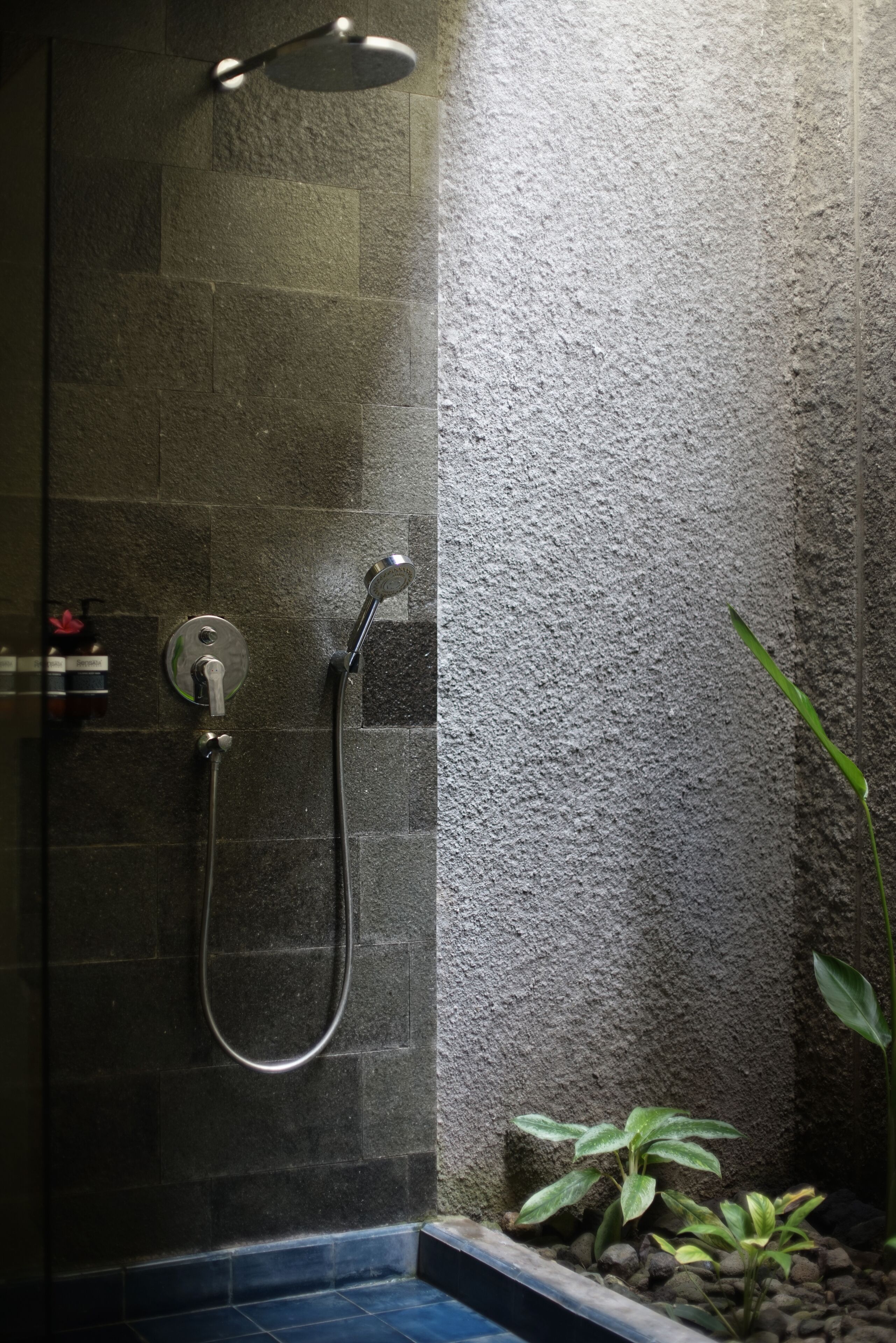 A shower area with a wall-mounted showerhead and a handheld showerhead.
