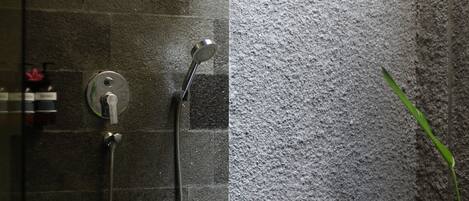 A shower area with a wall-mounted showerhead and a handheld showerhead.