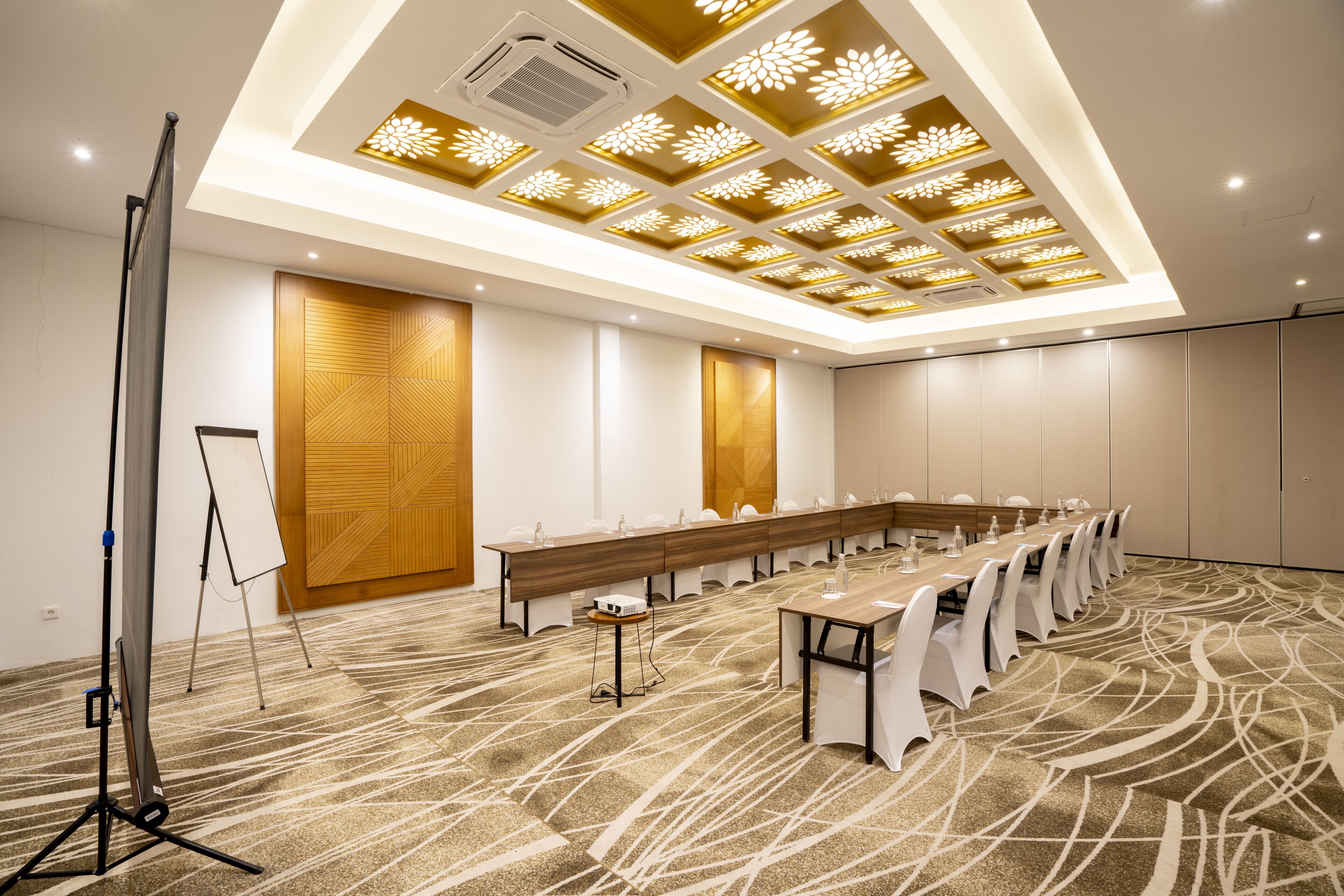 A conference room with a long table, white chairs, and a carpeted floor.