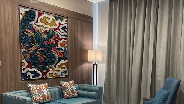 Una sala de estar moderna con un sofá color turquesa, un sillón azul, una mesa de centro redonda y un cuadro abstracto grande en la pared.