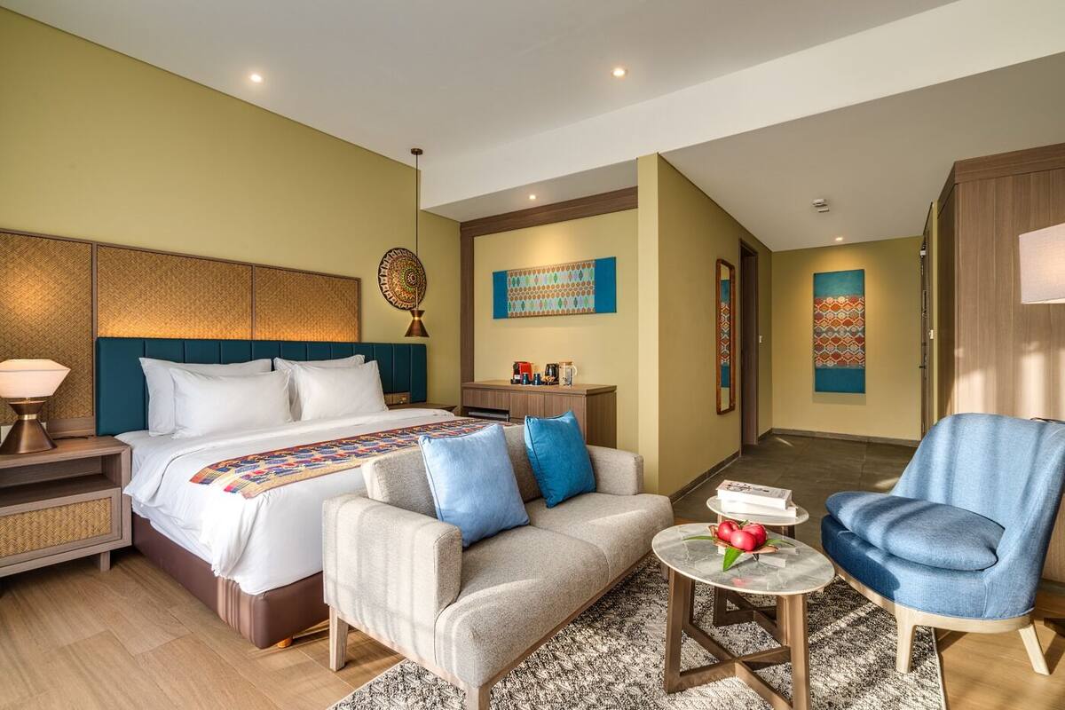Ein Hotelzimmer mit Bett, Sofa, Sessel, kleinem Tisch und Nachttisch.