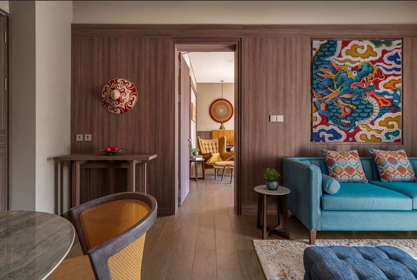 Een moderne woonkamer met een blauwe bank, een eettafel en een keuken die zichtbaar is door een open doorgang.
