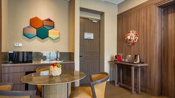 A modern kitchen with a round dining table, wicker chairs, and a fruit basket.
