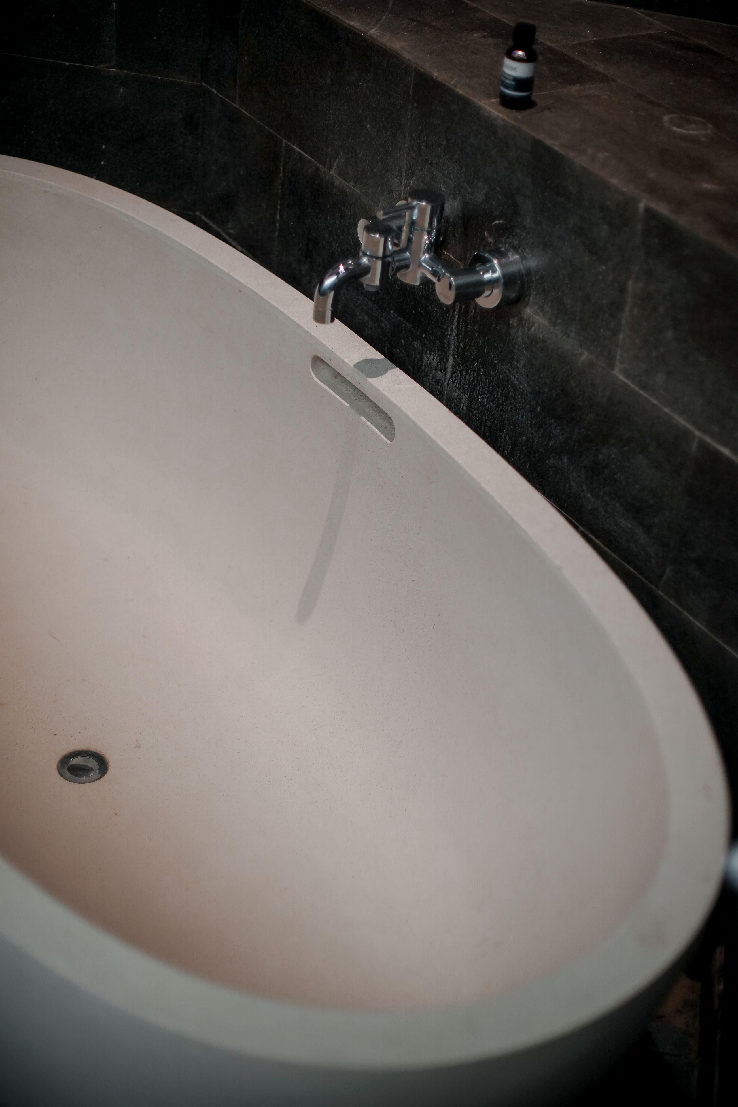 A bathtub with a faucet and a bottle of shampoo on the wall.