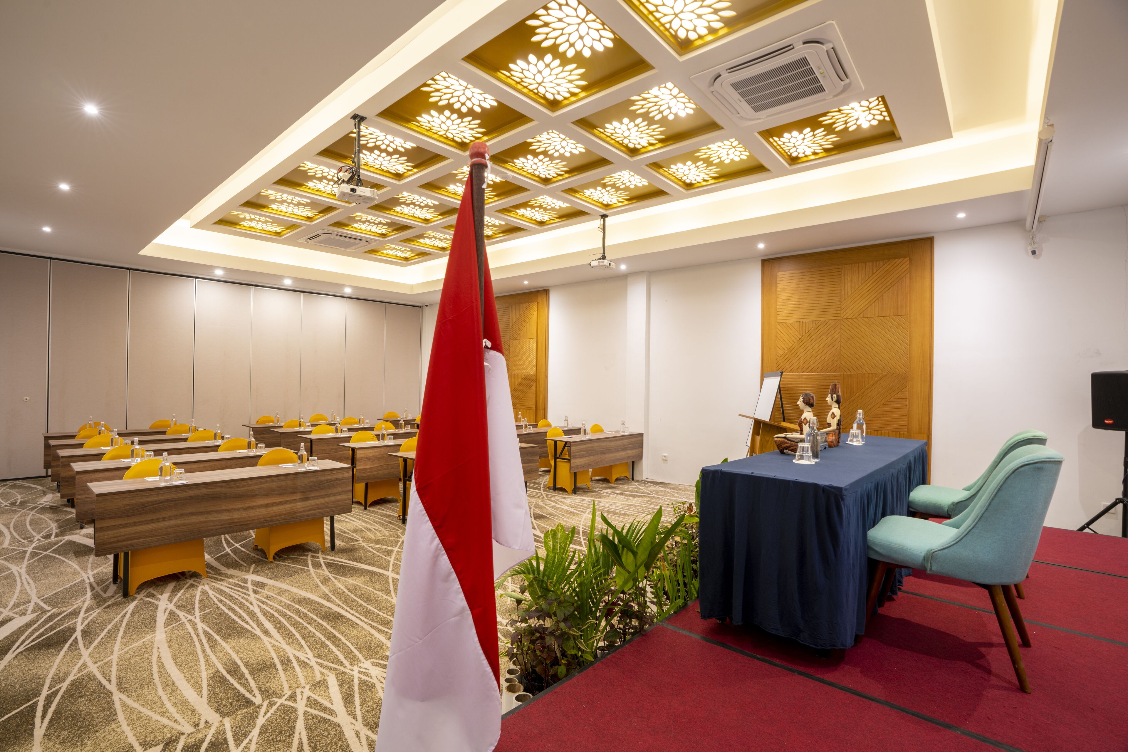 A conference room with tables, chairs, a flag, and a decorative ceiling.