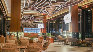 Un hall amplio con mobiliario de mimbre, una zona de bar y un cartel de Hotel Meruora.