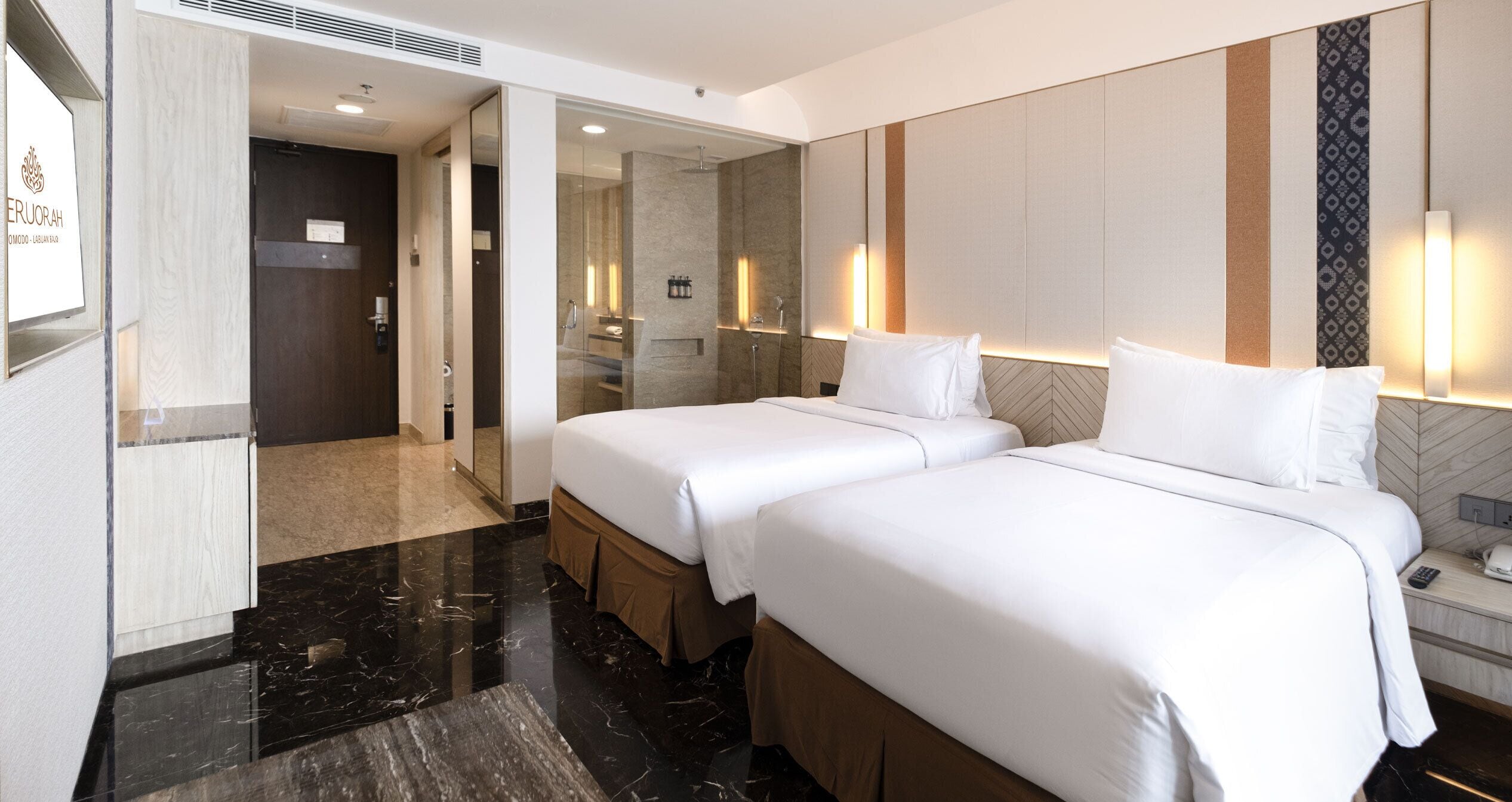 A hotel room with two beds, a bathroom with a shower, and a minibar.