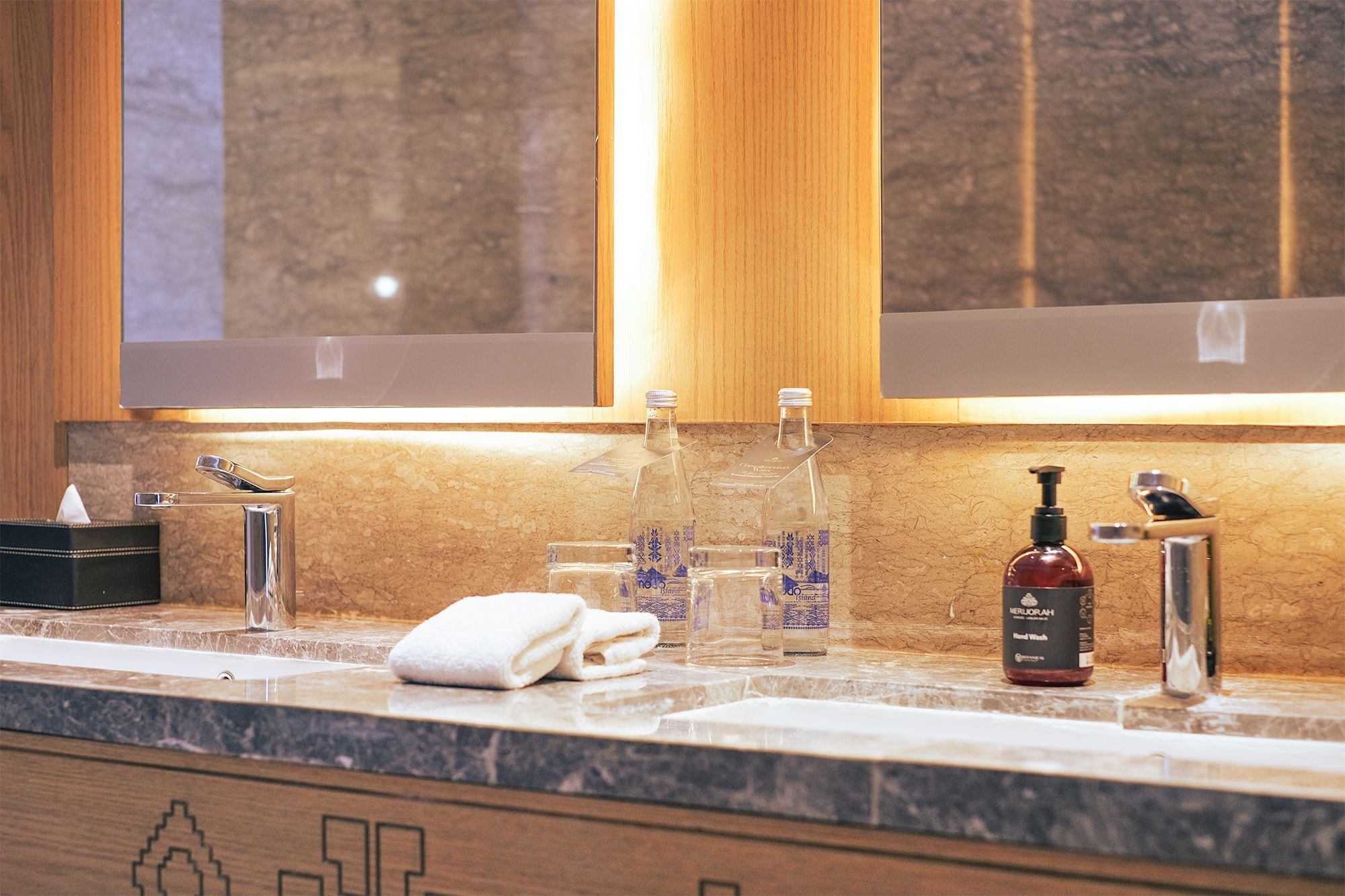 A bathroom with a marble countertop, a towel, and toiletries including a hand soap dispenser.