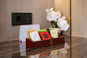 Una bandeja de madera con una tarjeta y tres bolsas de regalo sobre una superficie reflectante.