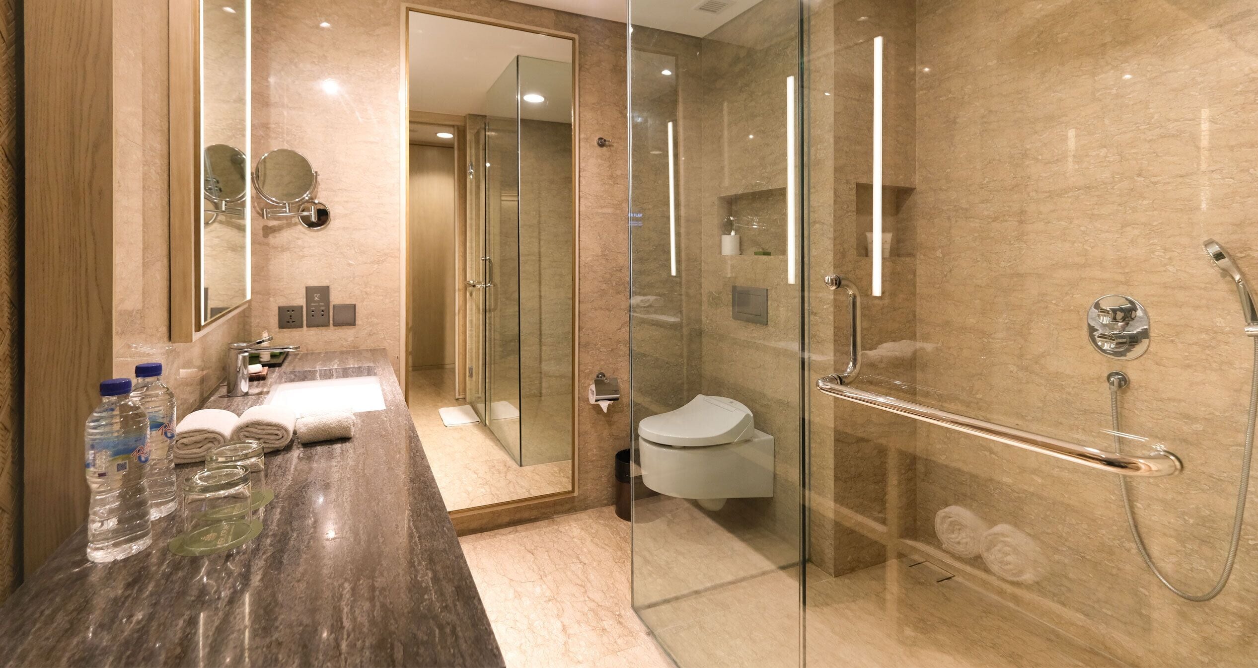 A modern bathroom with a glass-enclosed shower, a marble sink, and a toilet.